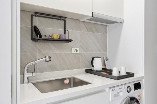 a white kitchen with a sink and a stove at 부산호텔그라체 Busan Hotel Grazie in Busan