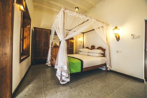 a bedroom with a bed with a canopy at Sisikirana Villa (Luxury Villa in Galle) in Unawatuna