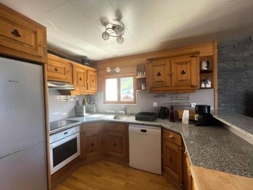 - une cuisine avec des placards en bois et des appareils blancs dans l'établissement Résidence Les Bleuets - Appartement Coup de coeur en Plein Centre de station avec cave privative MAE-5391, à Vénosc