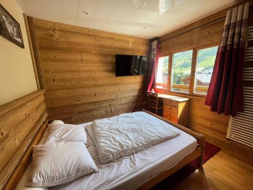 - une chambre avec un lit et un mur en bois dans l'établissement Résidence Les Bleuets - Appartement Coup de coeur en Plein Centre de station avec cave privative MAE-5391, à Vénosc