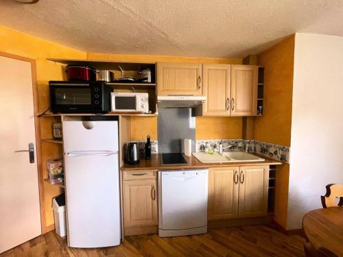 La cuisine est équipée d'un réfrigérateur blanc et d'un four micro-ondes. dans l'établissement Résidence Meije - Spacieux T3 avec coin montagne dans le village 1800, à deux pas des remontées mécaniques MAE-2441, à Vénosc