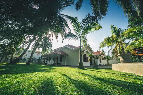 a house with palm trees in the yard at Sisikirana Villa (Luxury Villa in Galle) in Unawatuna