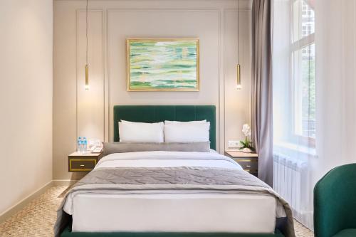 a bedroom with a large bed with a green headboard at Maestro Address Baku Hotel in Baku
