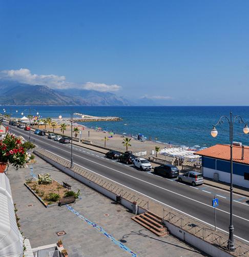 a road with cars parked on the side of a beach at Harmonia Home Capitello in Capitello
