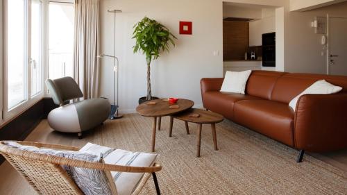 a living room with a brown couch and two tables at Valdemosa one in De Haan