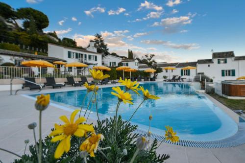 a swimming pool with umbrellas and yellow flowers at Le Hameau in Saint-Paul-de-Vence