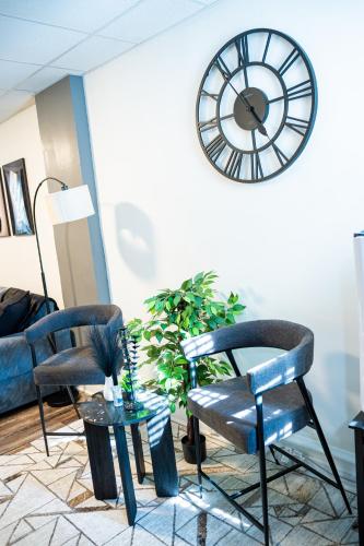 a living room with two chairs and a clock on the wall at The Cozy Grey Haven Home - 1st floor in Reading