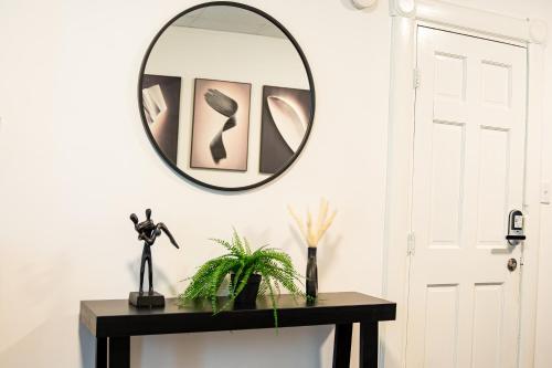 a mirror on a wall above a table with a plant at The Cozy Grey Haven Home - 1st floor in Reading