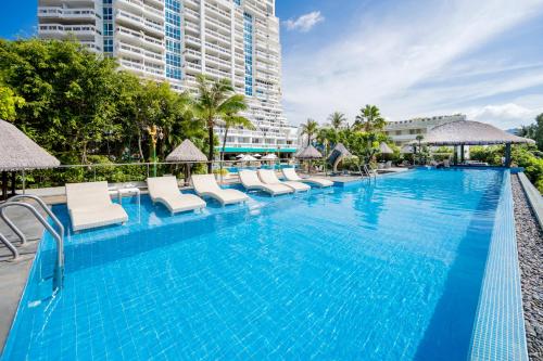a large swimming pool with chairs and umbrellas at Andaman Beach Suites Hotel, Patong Phuket in Patong Beach
