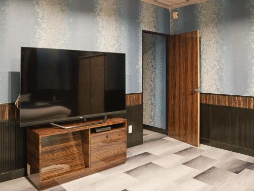 a large flat screen tv sitting on top of a wooden entertainment center at Tabist HOTEL SWEETWATER in Takamatsu