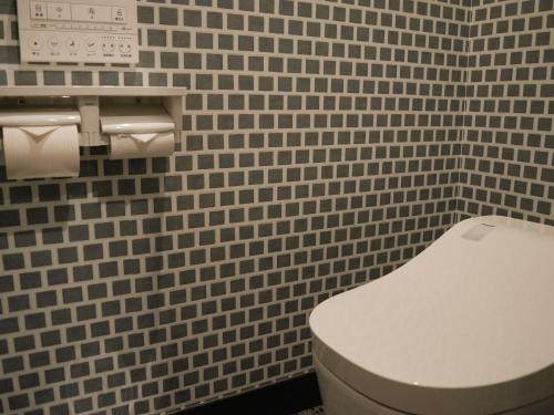 a bathroom with a white toilet and tiled walls at Tabist HOTEL SWEETWATER in Takamatsu