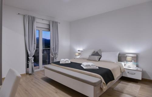 ein weißes Schlafzimmer mit einem großen Bett und einem Fenster in der Unterkunft Villa Neda Imotski-Makarska by Villas Guide in Zdilari