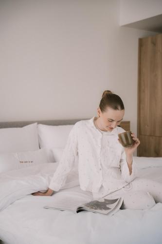a girl sitting on a bed holding a cup of coffee at FortyPlusOne Hotel Vienna in Vienna