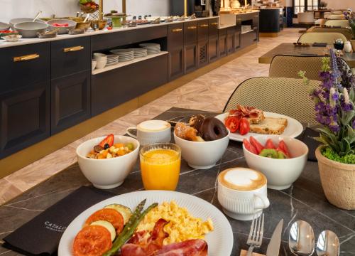 a table topped with plates of breakfast foods and orange juice at Catalonia Puerta del Mar in Málaga