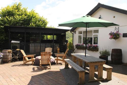 a patio with a picnic table and an umbrella at 3-Country retreat with outdoor kitchen and pizza oven! in Pont Sticill