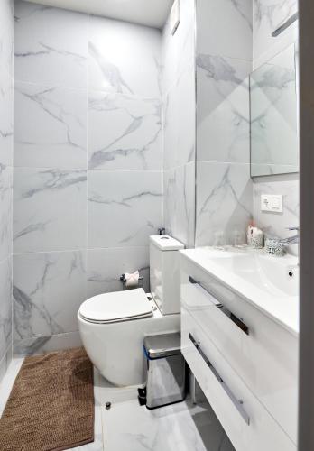 a white bathroom with a toilet and a sink at Apartamentos Golfinho Dourado in Santa Maria
