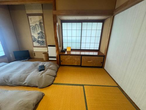 a room with two beds and a desk and windows at Azetoshi Lodge in Nozawa Onsen