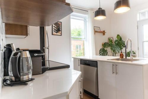 a kitchen with white counters and a sink and a stove at Appart lumineux et chaleureux in Montréal