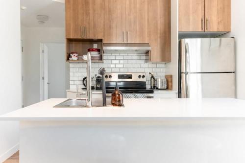 a white kitchen with a sink and a refrigerator at Appart lumineux et chaleureux in Montréal