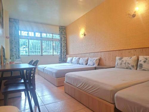 two beds in a room with a table and a desk at Taitung Moon House in Luye
