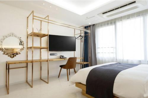 a bedroom with a bed and a desk and a television at Blanc Hotel & Resort in Yeosu