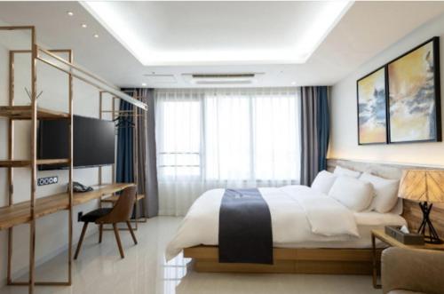 a bedroom with a large bed and a desk and a desk at Blanc Hotel & Resort in Yeosu