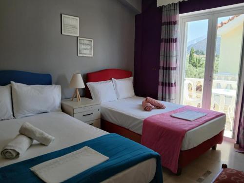 two beds in a room with a window at Helen's Seaside Apartment in Nafpaktos