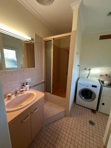 a bathroom with a sink and a washing machine at Comfortable 1 Bedroom Granny Flat with Parking Alexandra Hills in Ormiston
