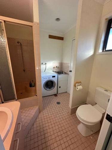 a bathroom with a toilet and a sink and a washing machine at Comfortable 1 Bedroom Granny Flat with Parking Alexandra Hills in Ormiston