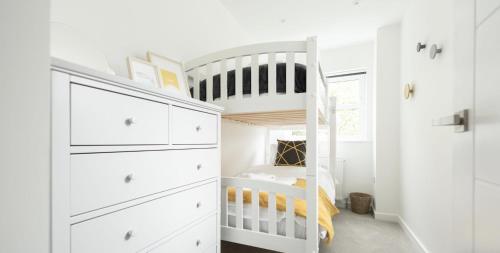 Una litera blanca en una habitación blanca con una cuna tipo litera. en VITAMYN SEA, 4 bed house, Sleeps 8, Sea views, 5 min walk to harbour and beaches, en St Ives