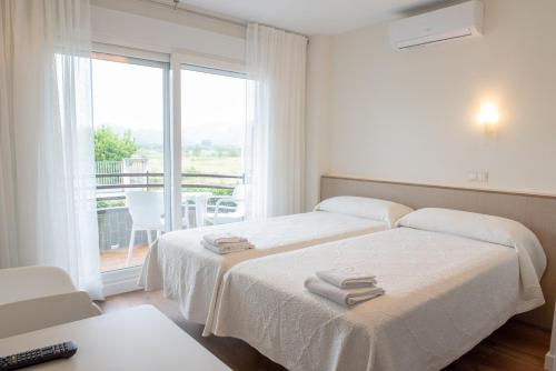 two beds in a white room with a window at Apartamentos Suaces in Noja