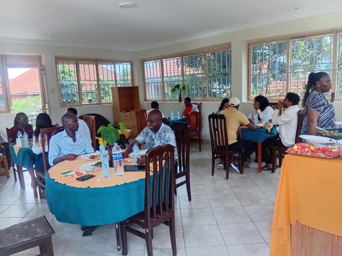 a group of people sitting at tables in a restaurant at Pacific Cottages and Guest House Jinja in Jinja