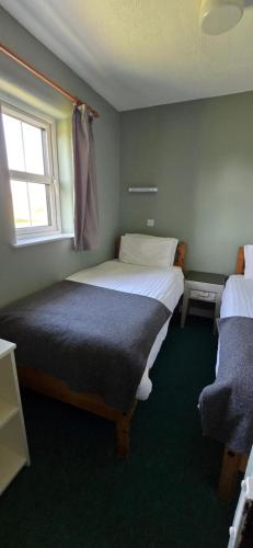 a bedroom with two beds and a window at Holly Cottage 3 Bedroom in Louisburgh