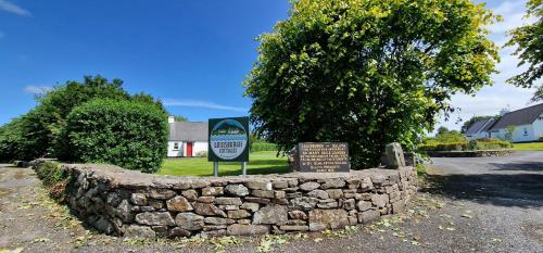 a stone wall with a sign in front of it at Holly Cottage 3 Bedroom in Louisburgh