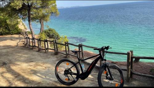 a bike parked next to a fence next to the ocean at Sani Nature Retreat - Elegant Stay by Forest and Sea in Sani Beach