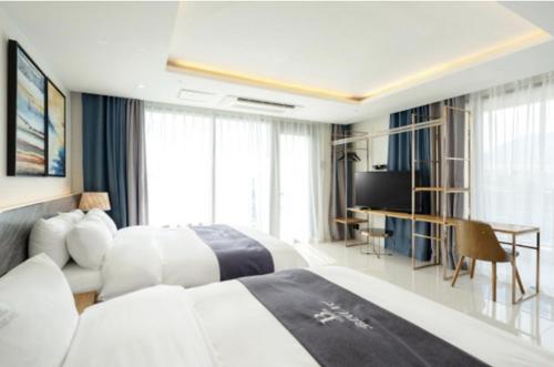 a hotel room with two beds and a desk at Blanc Hotel & Resort in Yeosu