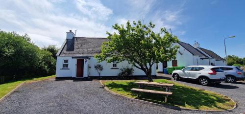 a white house with a car parked in front of it at Bluebell Cottage 3 bedroom in Louisburgh
