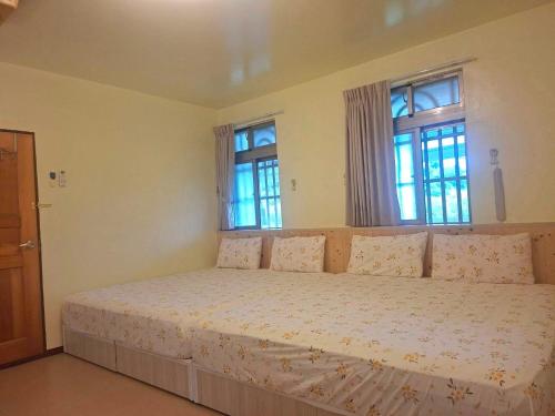 a bedroom with a large bed with two windows at Taitung Moon House in Luye
