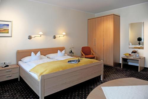 ein Hotelzimmer mit einem Bett und einem Stuhl in der Unterkunft Hotel-Pension Pöhling in Lippstadt