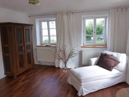 a living room with a white couch and two windows at Freiraum Ferienwohnung in Dießen am Ammersee