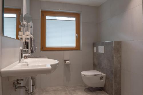 a bathroom with a sink and a toilet and a window at Beim Kathrein - inklusive SILVRETTA Card Premium in Galtür