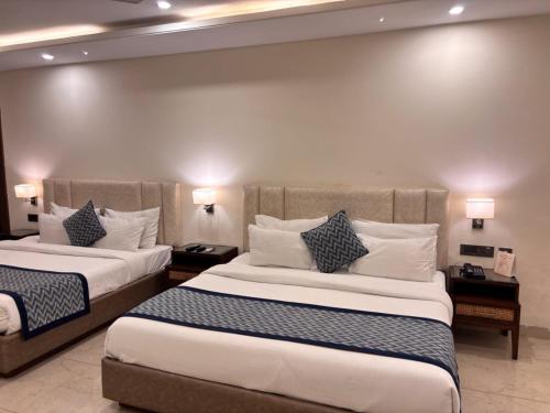 a hotel room with two beds and two lamps at Mj Aero Suite in Dehradun Airport