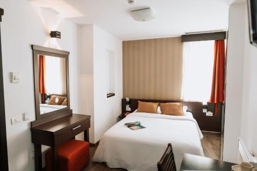 a bedroom with a bed and a desk and a mirror at Hotel Duke Armeneasca City Center in Bucharest