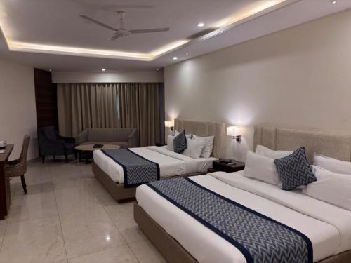 a hotel room with two beds and a table at Mj Aero Suite in Dehradun Airport