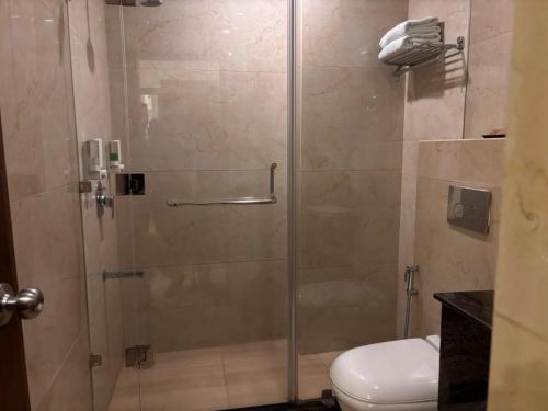 a glass shower with a toilet in a bathroom at Mj Aero Suite in Dehradun Airport