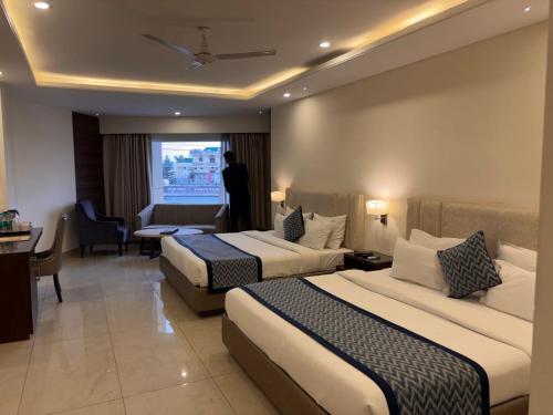 a hotel room with two beds and a person looking out the window at Mj Aero Suite in Dehradun Airport