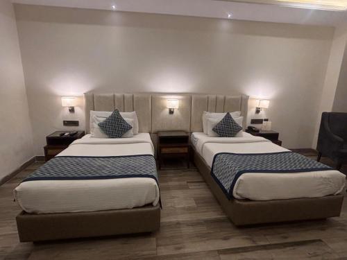 a hotel room with two beds and two lamps at Mj Aero Suite in Dehradun Airport