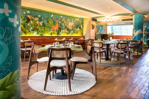 a restaurant with tables and chairs and a large painting at IZE Seminyak by LifestyleRetreats in Seminyak