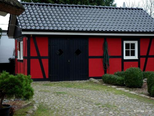 eine rote und schwarze Scheune mit weißem Fenster in der Unterkunft Landhaus Uhlenhof 4 in Groß Zicker