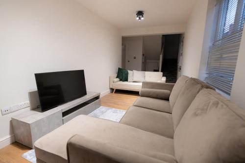 a living room with a couch and a flat screen tv at D'Luxe 3 - 5 beds En-suite Home in London in Isleworth